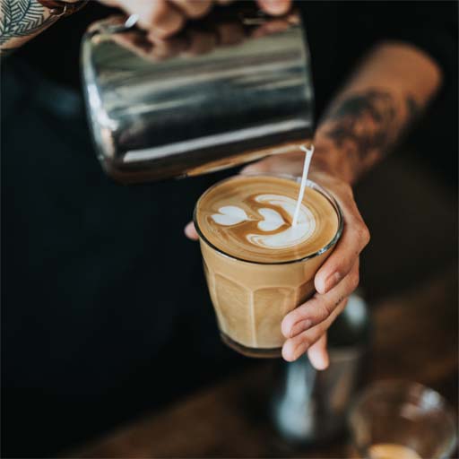 Ein erfahrener Barista zaubert Latte Art Cafe auf einen köstlichen Cappuccino.